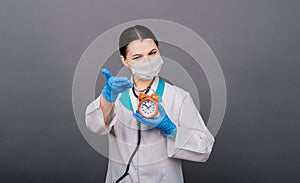 Smiling doctor woman pointing on clock, time to vaccine