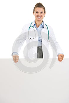 Smiling doctor woman showing blank billboard