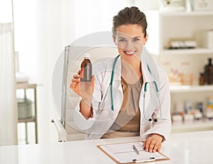 Smiling doctor woman showing medicine bottle