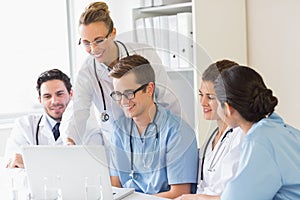 Smiling doctors and nurses discussing over laptop