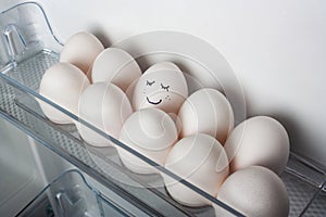 Smiling egg in a row of white eggs in fridge