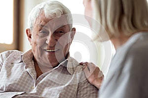 Smiling elder male patient communicating with nurse.