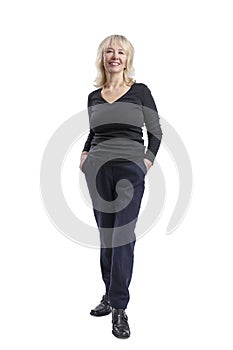 Smiling elderly blonde woman. A beautiful lady in a black sweater and blue trousers stands with her hands in her pockets. Activity