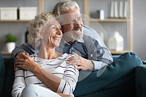 Smiling elderly couple look in distance dreaming