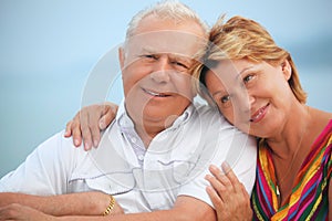 Smiling elderly couple on veranda near seacoast