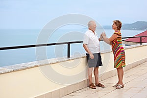 Smiling elderly couple on veranda near seacoast