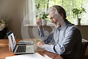 Smiling elderly man grandfather having virtual consultation with female doctor