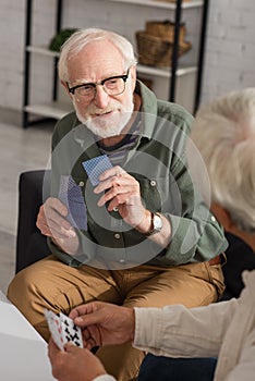 Smiling elderly man holding playing cards