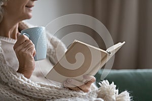 Smiling elderly senior woman drinking tea, reading paper book. photo