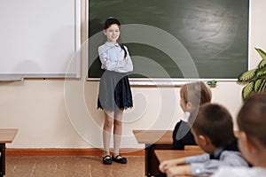 Smiling elderly teacher near the chalkboard asking student at the math lesson