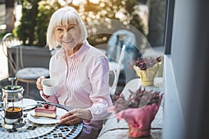 Smiling elderly woman enjoying tea outdoors