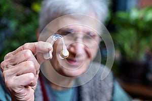 smiling elderly woman holding a hearing aid