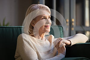 Smiling elderly woman look in distance enjoying pleasant memories