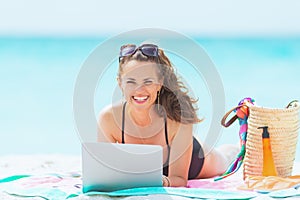 Smiling elegant 40 year old woman on white beach using website