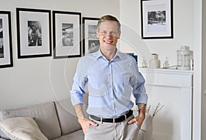 Smiling elegant 60s senior man standing at home looking at camera, portrait.