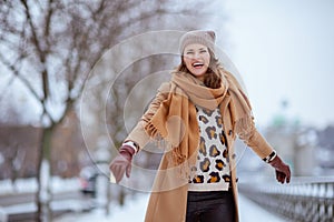 smiling elegant female in brown hat and scarf in camel coat