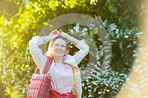 smiling elegant female in pink dress and white jacket in city