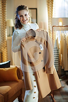 Smiling elegant housewife holding on hanger purchased new coat