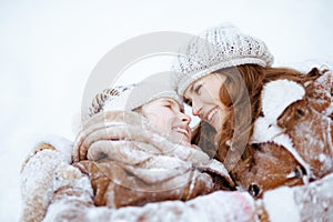Smiling elegant mother and child laying in snow