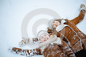 smiling elegant mother and child making snow angel