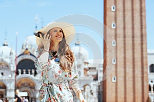 Smiling elegant tourist woman in floral dress talking on phone