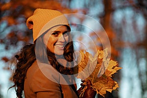 Smiling elegant woman in brown coat and yellow hat
