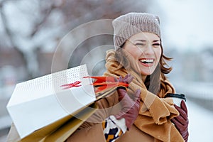 smiling elegant woman in brown hat and scarf in camel coat