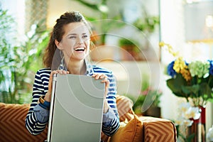 Smiling elegant woman holding laptop while sitting on divan