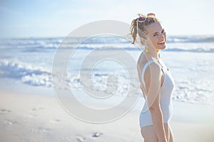 smiling elegant woman in white swimwear at beach relaxing