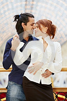 Smiling embracing couple stands leaned on banister photo