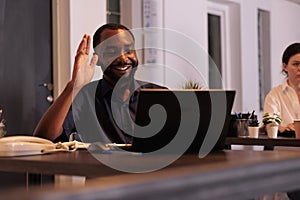 Smiling employee talking on videoconference with teamlead, waving hi