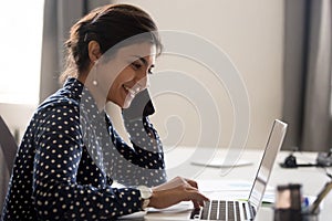 Smiling employee working on laptop talking over phone