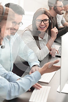 Smiling employees of call center talk sitting behind a Desk