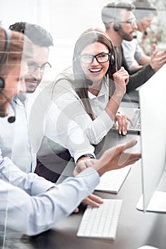 Smiling employees of call center talk sitting behind a Desk