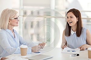 Smiling employees discuss paperwork statistics at company meeting