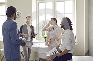 Smiling employees have pleasant conversation discussing work at meeting in office.