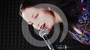 Smiling energetic woman singing song into microphone. Vertical video