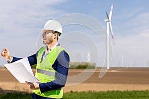 Smiling Engineer Reviewing Plans Near Wind Turbines on a Sunny Day. Generative AI