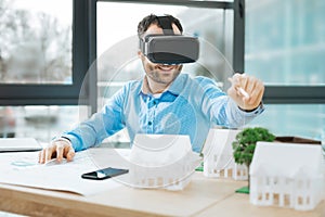 Smiling engineer using VR headset while designing construction photo