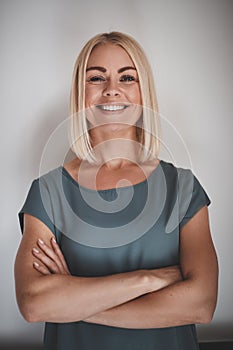 Smiling entrepreneur with her arms crossed against a gray backgr