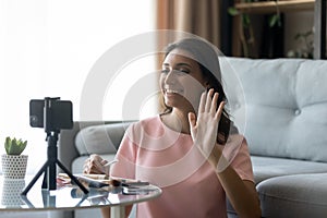 Smiling ethnic woman blogger shoot cosmetics haul on cellphone