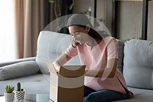 Smiling ethnic woman unpack postal package shopping online