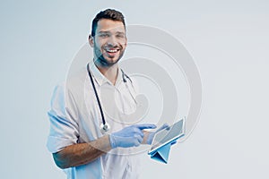 Smiling european male doctor using digital tablet