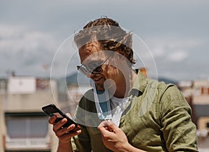 Smiling european man taking off protective mask to unblock the phone. The man is happy to be free and meet with friends. photo