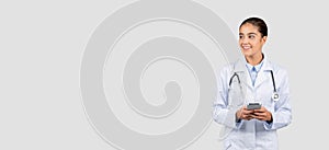 Smiling european millennial lady doctor in white coat, with stethoscope, chatting by phone