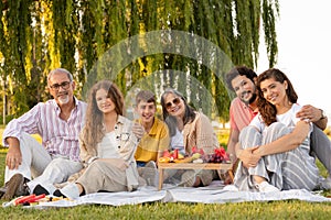 Smiling european multi-generation family enjoying picnic, fruits, food in park