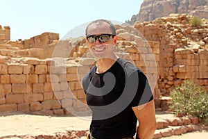 Smiling europian tourist man in sunglasses and black wear in Petra in Jordan during a journey