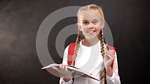 Smiling excellent student with copybook holding pen, readiness sign, education