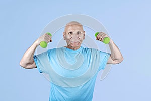 Excited pensioner practising bodybuilding exercising with dumbbells