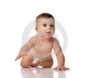 Smiling excited infant baby toddler in diaper is crawling on all fours slapping his hands on the floor